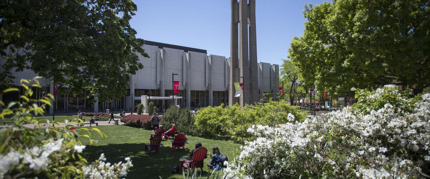Students sitting on lawn chairs by the Bell Tower in the spring.